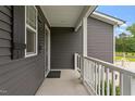 Side porch with sleek gray siding, white railing, and lush greenery at 852 Cokesbury Park Lane Ln, Fuquay Varina, NC 27526
