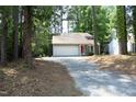 A single-story house nestled amongst the trees has an attached garage and long drive at 1110 Elmira Ave, Durham, NC 27707