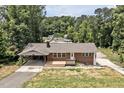 Birds eye view of the red brick house featuring a carport, and a large front yard surrounded by woods at 112 S Joyland St, Durham, NC 27703