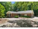 Well-maintained brick home featuring a lush lawn, mature trees, and gravel driveway at 1134 Deerfoot Trail Trl, Sanford, NC 27332