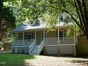 Inviting home featuring a cozy porch, stairs leading up to the door, and green landscaping at 129 Clark Ct, Youngsville, NC 27596