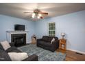 Comfortable living room featuring a fireplace, ceiling fan, and a window with natural light at 129 Clark Ct, Youngsville, NC 27596