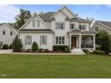 Charming two-story home with white brick, wood trim and gray shutters surrounded by a lush, green lawn at 2077 Amalfi Pl, Apex, NC 27502