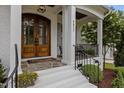 Inviting entryway with a striking wood double-door, column supports, and charming porch seating at 2077 Amalfi Pl, Apex, NC 27502
