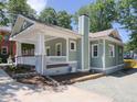 View of the side exterior of the light green home, with a white porch, columns, and chimney at 2106 University Dr, Durham, NC 27707