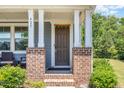 Inviting covered front porch with brick columns, seating, and a decorative door hanging at 425 Liberty Hill, Morrisville, NC 27560