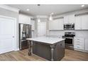 Bright, modern kitchen features stainless appliances, white cabinetry, and a large center island with pendant lighting at 453 Granite Saddle Dr, Rolesville, NC 27571