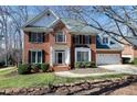 Traditional brick home featuring black shutters, a 2-car garage, mature trees, and green lawn at 511 Windstream Way, Cary, NC 27518