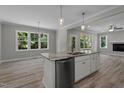 Modern kitchen island with stainless steel dishwasher and sink, with views of living and dining area at 5601 Preston Pl, Raleigh, NC 27604