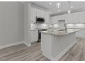 Modern kitchen features white cabinets, stainless steel appliances, granite counters and pendant lights over the island at 5601 Preston Pl, Raleigh, NC 27604