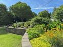 Exquisite landscaping with vibrant flowers, lush greenery, and elegant stone retaining walls at 582 Wimbleton Dr, Raleigh, NC 27609