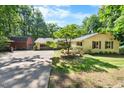 Exterior of beautiful home with large, landscaped front yard, mature shade tree, and two-car garage at 5822 Country Lane Dr, Durham, NC 27705