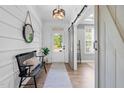 Elegant foyer featuring wood floors, a stylish bench, decorative mirror and view to the office via a sliding barn door at 6404 Fauvette Lane Ln, Holly Springs, NC 27540