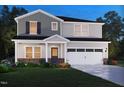 Charming two-story home with gray siding, brick accents, landscaped flower beds, and a welcoming front porch at 740 Deschutes Dr, Garner, NC 27529