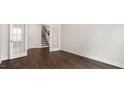 Open living room featuring dark hardwood floors, an open doorway, and staircase access at 79 Bronco Pace Dr, Clayton, NC 27520