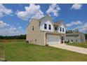 Side view of a two-story home featuring neutral siding, a white garage, and a well-maintained lawn at 935 Bombardier Ln, Spring Hope, NC 27882