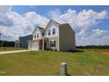 Angle view of a two-story home featuring neutral siding, a white garage, and a well-maintained lawn at 935 Bombardier Ln, Spring Hope, NC 27882