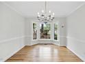 Bright dining room with hardwood floors, chandelier, and bay windows overlooking yard at 103 Oxford Cir, Knightdale, NC 27545