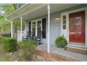 Inviting front porch with rocking chairs, potted plants, and a red front door at 103 Oxford Cir, Knightdale, NC 27545