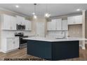 Modern kitchen featuring stainless steel appliances, white cabinets, a large island, and pendant lighting at 109 Drew St, Louisburg, NC 27549