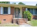 Close-up of the brick front porch with a metal railing and painted front door at 1209 Landon St, Durham, NC 27703