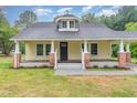 Classic yellow house with a cozy front porch, brick accents, and freshly landscaped flower beds at 1398 Tarboro Rd, Youngsville, NC 27596