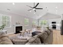 Open-concept living room with a fireplace, vaulted ceilings, and hardwood floors leading to kitchen at 154 Buckaroo Dr, Louisburg, NC 27549