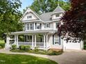 Attractive two-story home with a grand front porch, lush landscaping, and an attached garage at 1702 Mcrae Pl, Hillsborough, NC 27278