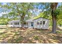Charming home exterior with lush green trees, a manicured lawn, fresh landscaping, and a freshly painted white brick at 2003 Broadway Rd, Sanford, NC 27332