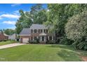 Traditional two-story brick home with an attached garage and a well-maintained lawn surrounded by mature trees at 418 Old Scarborough Ln, Garner, NC 27529