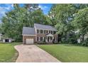 Classic two-story brick home with an attached garage, long driveway, and a well-manicured lawn with mature trees at 418 Old Scarborough Ln, Garner, NC 27529