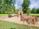 Outdoor patio with a wood-burning brick oven, comfortable seating, and lush greenery, perfect for entertaining at 4200 Harmony Church Rd, Efland, NC 27243