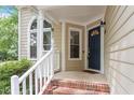 Inviting front porch with brick steps, white railings, and an arched window to bring in natural light at 4401 Liverpool Ln, Raleigh, NC 27604