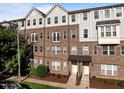Attractive brick townhome with a covered entryway, manicured landscaping, and gray shingle siding on the upper floors at 531 N Person St # 205, Raleigh, NC 27604