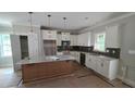 Modern kitchen with white cabinets, a center island, stainless steel appliances, and stylish pendant lighting at 55 Stream View Way, Spring Hope, NC 27882