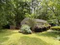 Backyard features a small deck and green lawn surrounded by mature trees and established plantings at 101 Solway Ct, Cary, NC 27511
