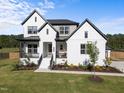 Charming home showcasing a black roof, white painted brick, covered porch and a beautiful lawn at 105 Scotland Dr, Youngsville, NC 27596