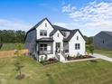 Stylish home featuring a black roof, gray and white painted brick, covered porch and a green lawn at 105 Scotland Dr, Youngsville, NC 27596