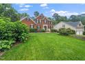 Gorgeous brick home with a lush green lawn, mature trees, and well-maintained landscaping at 112 Sterling Ridge Way, Cary, NC 27519