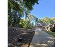 View of the front yard with driveway leading up to the brick home with mature trees surrounding the property at 119 Comanche Dr, Louisburg, NC 27549