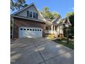 Brick and vinyl home with attached two-car garage and mature landscaping in front yard at 119 Comanche Dr, Louisburg, NC 27549