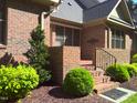 Brick front porch with a small evergreen tree, shrubbery and mulch at 12 Crail Ct, Durham, NC 27712