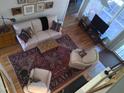 Living room with sofa, armchairs, area rug, hardwood floors and many windows at 12 Crail Ct, Durham, NC 27712