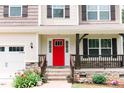 Close up of a charming front porch with stone detail, colorful landscaping and a bright red front door at 123 Scheer Ave, Durham, NC 27703