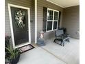 Inviting front porch with a stylish door, seasonal wreath, cozy seating, and charming decorative accents at 137 Campaign Dr, Mebane, NC 27302