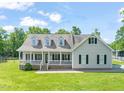 A well-manicured lawn highlights the exterior of this two-story home featuring a classic front porch and gray siding at 1717 Ormond Rd, Hurdle Mills, NC 27541
