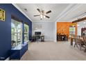 Bright living room with large windows, a ceiling fan, and neutral carpeting leading into the dining area at 2909 Landon Pines Ct, New Hill, NC 27562