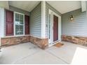 Home's welcoming front porch featuring gray siding, a dark-colored front door, and stone accents at 4502 Joe Cotton Dr, Knightdale, NC 27545