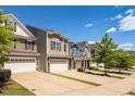 A row of charming townhomes, each boasting a unique facade and a two-car garage under a bright sky at 512 Barneswyck Dr, Fuquay Varina, NC 27526