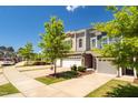 A street view showcasing townhomes with stone accents, garages, and tidy landscaping under a clear blue sky at 512 Barneswyck Dr, Fuquay Varina, NC 27526